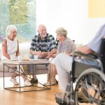 group of older adults sitting at round a coffee table having a conversation