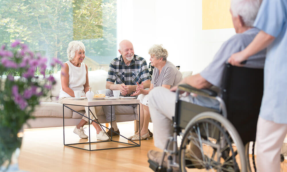 elderly people sitting around coffee table talking