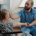 Male nurse aiding patient in memory care with assisted living