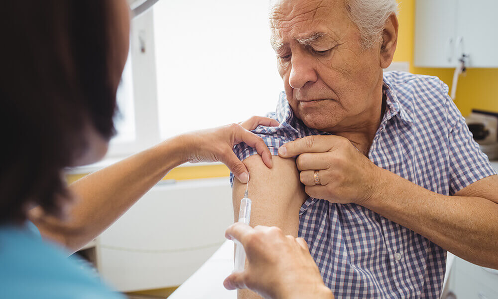 an elderly man getting his seasonal vaccinations