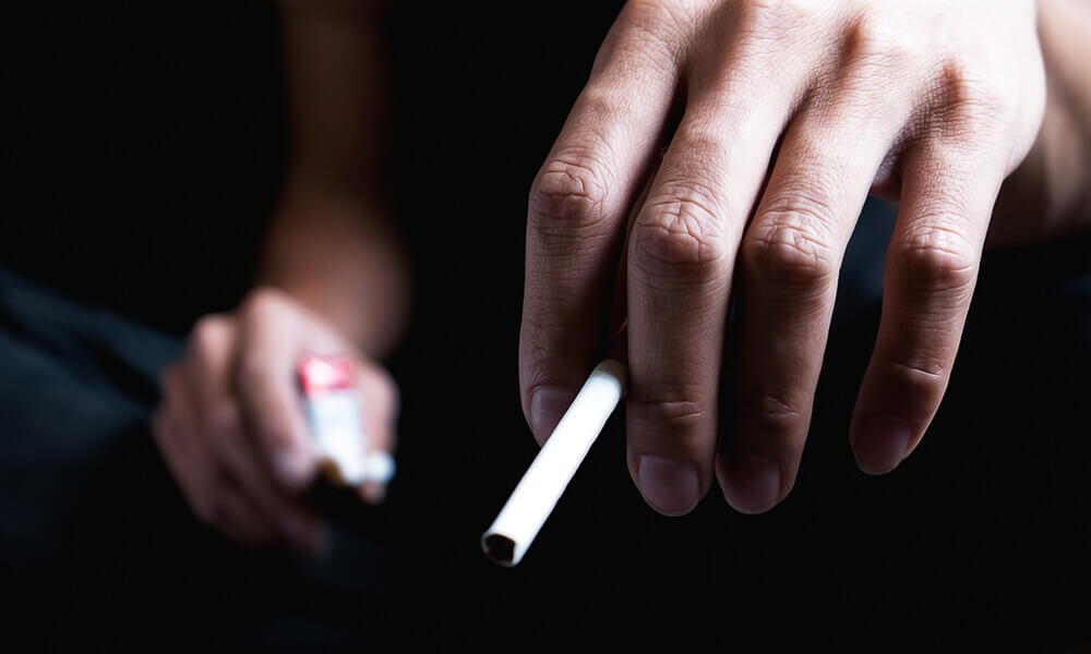 a young man holding a cigarette hoping to become a cigarette quitter