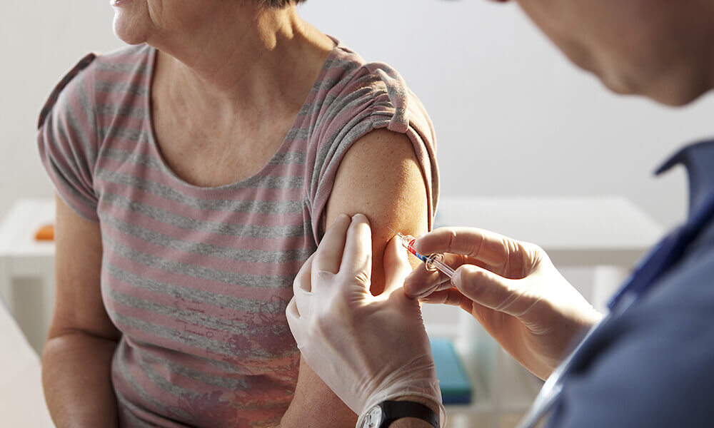 an elderly woman getting her seasonal vaccinations