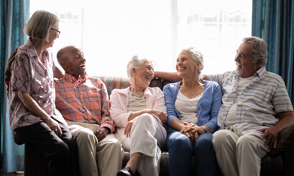 a group of retirees hanging out on a couch laughing together